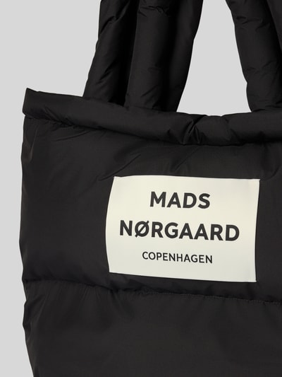 Produktfoto, Handtasche mit Label-Detail und Steppnähten von MADS NØRGAARD, schwarze Oberfläche, rechteckige Form, sichtbare Textur.