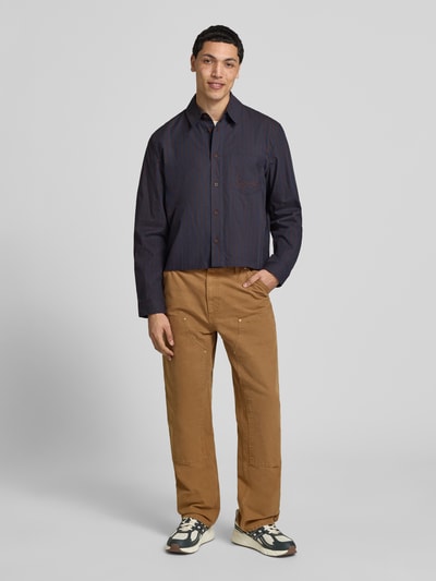 Mannenmodel draagt Relaxed Fit vrijetijdsoverhemd met borstzak van KARL KANI, puur katoen, met lange mouwen, kentkraag en knoopsluiting, gestikt logo, vooraanzicht volledige lichaamsopname.