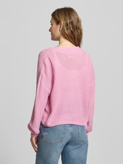 Frauenmodel trägt Regular Fit Strickjacke mit einreihiger Knopfleiste Modell 'CAROL NICE' von Only in Rosa, Strickoptik, Ganzkörperansicht Rückansicht.