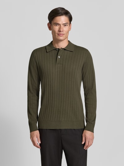 Männermodel trägt Regular Fit Poloshirt aus reiner Baumwolle Modell 'TORINO' von Selected in Olivgrün, vertical gerippt, Ganzkörperansicht von vorne.