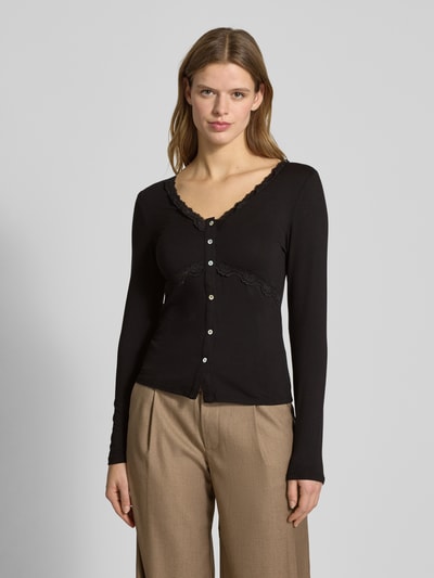 Modelka kobieca nosi Slim Fit Langarmshirt aus Viskose-Mix Modell 'SINI' von Only, czarna, jednokolorowa, ozdobiona koronką, z dekoltem w serek i długimi rękawami, widok całej sylwetki z przodu.