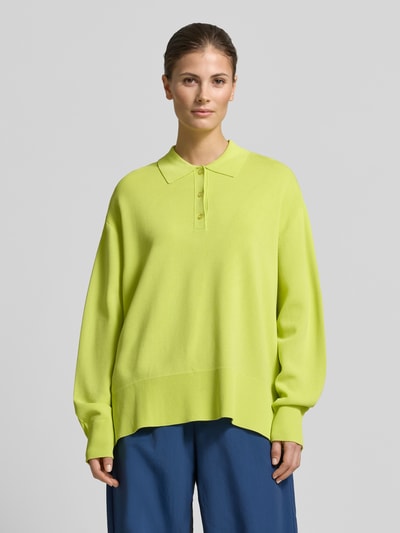 Vrouwenmodel draagt Strick-Polohemd im Wide Fit - curated by Tinvcb van SIC, geelgroene gebreide look, relaxed fit, polokraag, elastische mouwboorden, ruglengte 62 cm, mouwlengte 56 cm, long sleeve, voorkant bovenlichaam close-up.