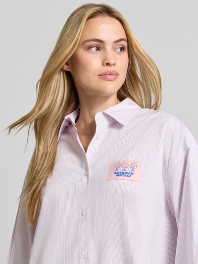 Frauenmodel trägt Oversized Hemdbluse aus Baumwoll-Mix Modell 'SOABIRD' von American Vintage, feines Streifenmuster, Logo-Patch, Nahaufnahme Oberkörper.
