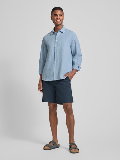 Männermodel trägt Regular Fit Freizeithemd aus Leinen-Baumwoll-Mix Modell 'CLAY LINENBLEND' von SELECTED HOMME in Melange-Optik, Kentkragen, durchgehende Knopfleiste, langarm, 2-Knopf-Manschette, Rückenpasse, Flammgarn Materialverarbeitung, leicht abgerundeter Rumpfabschluss, Ganzkörperansicht von vorne.