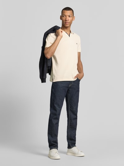 Männermodel trägt Modern Fit Poloshirt mit Logo-Stitching von Christian Berg Men in Beige, reine Baumwolle, Ganzkörperansicht von vorne.