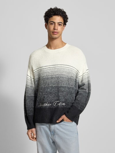 Męski model nosi Oversized Strickpullover mit gerippten Abschlüssen von ANOTHER COTTON LAB, mieszanka materiałów z dodatkiem wełny, prążkowane wykończenia, okrągły dekolt, wyhaftowane logo, długość tyłu 68 cm, długość rękawów 55 cm, szaro-czarne cieniowanie, całkowity widok z przodu.