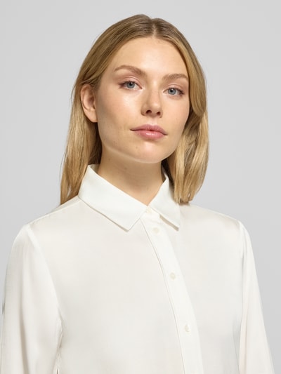 Frauenmodel trägt Regular Fit Hemdbluse aus Viskose Modell 'Fanda' von OPUS in Weiß mit Hemdblusenkragen und Knopfleiste, Nahaufnahme Oberkörper.