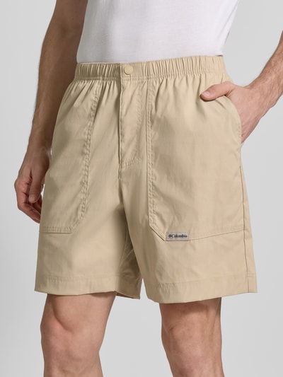 Männermodel trägt Regular Fit Shorts mit Logo-Patch Modell 'Landroamer' von COLUMBIA in Beige, elastischer Bund, aufgesetzte Taschen, Nahaufnahme Oberkörper.