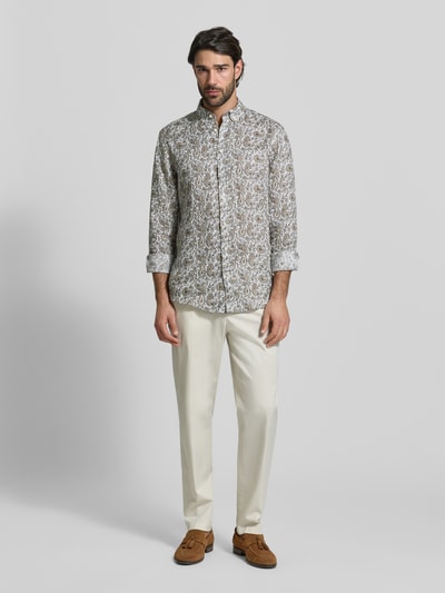 Männermodel trägt Regular Fit Leinenhemd aus reinen Leinen von Christian Berg Men mit Allover-Paisley-Print, Knopfleiste, Button-Down-Kragen und Sportmanschetten, helle Naturtöne, Ganzkörperansicht von vorne.