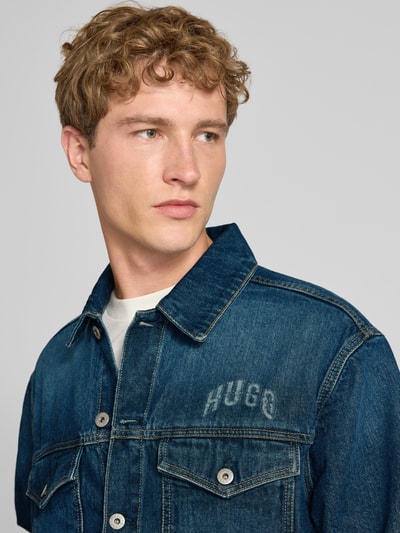 Męski model trägt Regular Fit Jeansjacke aus reiner Baumwolle Modell 'Dex' von HUGO, niebieski denim, tekstura bawełny, Nahaufnahme Oberkörper. Kurtka jeansowa HUGO Blue.