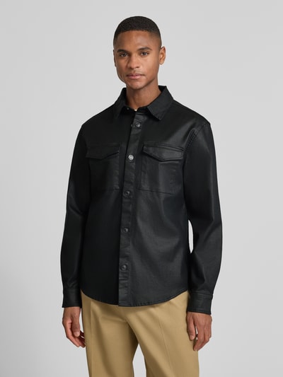 Männermodel trägt Regular Fit Hemdjacke mit Brusttaschen Modell 'THEO' von Guess, schwarze Baumwoll-Viskose, Ganzkörperansicht von vorne.