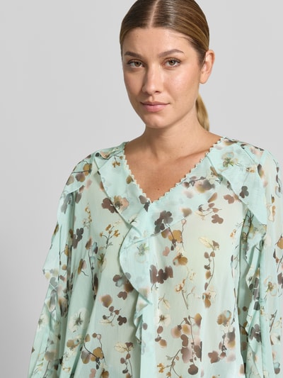 Vrouwenmodel draagt Bluse im Allover-Look mit Volants van Marc Cain in mintgroen met bloemenpatroon, regular fit, v-hals, volants, ruglengte bij maat 36: 60 cm, mouwlengte bij maat 36: 64 cm, detailopname bovenlichaam.
