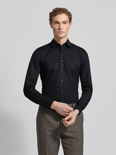Męskim model nosi Super Slim Fit Business-Koszulę z kołnierzykiem typu kent od OLYMP No. Six, mieszanka bawełny i elastanu, listwa guzikowa, długość tyłu 81 cm, szerokość ramion 41 cm, długość rękawów 67 cm, krój slim fit, kolor czarny, gładka faktura, pełny widok z przodu.