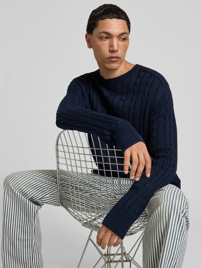 Männermodel trägt Slim Fit Pullover in Strick-Optik von Filippa K in Dunkelblau, reine Baumwolle, Rundhalsausschnitt, Nahaufnahme Oberkörper.
