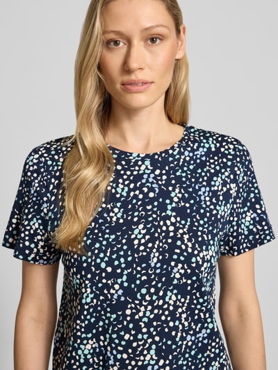 Modelka kobieca nosi Regular Fit T-Shirt aus reiner Baumwolle von Tom Tailor, efekt: wzór na całej powierzchni, aplikacja: naszywka z logo, okrągły dekolt, rękaw: krótki, zakończenie rękawów: proste, wykończenie materiału: dżersej, materiał: czysta bawełna, krótki rękaw, abstrakcyjny wzór w kropki, kolory granatowy, błękitny, beżowy, jasny zielony, struktura miękka, Nahaufnahme górnej części ciała