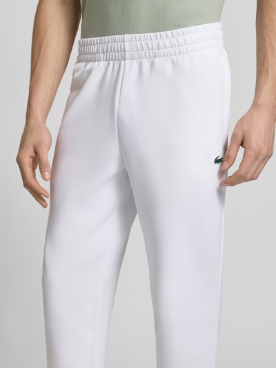 Männermodel trägt Tapered Sweatpants mit Baumwoll-Anteil von Lacoste Sport, weiß, unifarben, Logo-Patch, Nahaufnahme Oberkörper.