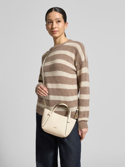 Frauenmodel trägt Handtasche mit Strukturmuster Modell 'Cosmo' von Abro in Beige mit Logo-Applikation, Nahaufnahme Oberkörper.