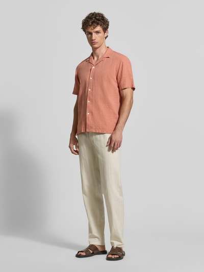 Męski model nosi Hose aus Leinen-Baumwoll-Mix mit elastischem Bund od Lindbergh, krój regular fit, jasny beż, widoczne kieszenie, szerokość w rozmiarze M: 40 cm, długość nogawki wewnętrznej w rozmiarze M: 79 cm, zdjęcie całej sylwetki z przodu.