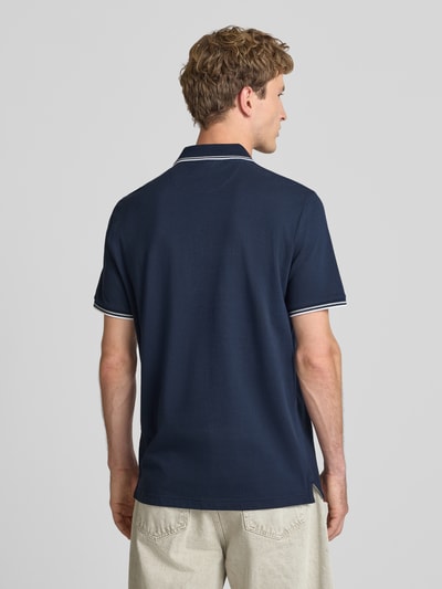 Männermodel trägt Slim Fit Poloshirt mit Label-Stitching van CHAMPION in donkerblauw, puur katoen, ruglengte bij maat M 73 cm, ganzkörperansicht rückansicht.