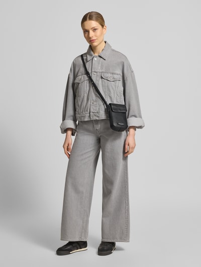 Frauenmodel trägt Umhängetasche aus echtem Leder von Marc O'Polo, unifarben, glatte Nappaleder-Textur, Hauptfach, Label-Applikation, Ganzkörperansicht von vorne.