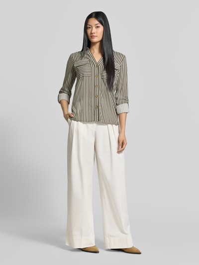 Frauenmodel trägt Regular Fit Langarmbluse aus reiner Viskose Modell 'BUMPY' von VERO MODA, olivgrün gestreift, kombiniert mit weiter cremeweißer Hose, glatte Textur, Ganzkörperansicht von vorne, Damen Langarmbluse von VERO MODA.