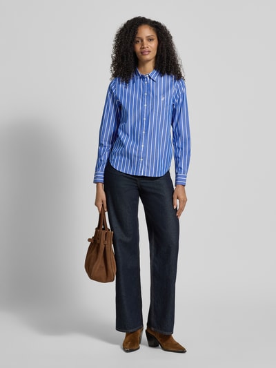 Modelka nosi Regular Fit Bluse mit Brusttasche und Label-Stitching od Gant, bawełna, kołnierz koszulowy, granatowy, białe paski, widok całej sylwetki z przodu.