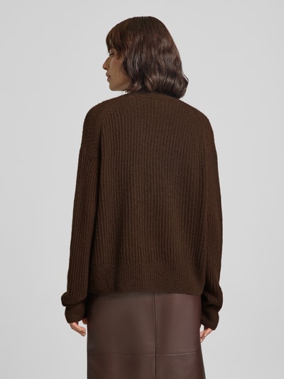 Frauenmodel trägt Strickjacke aus Alpaka-Mix mit V-Ausschnitt von Closed in dunklem Braun, grob gestrickte Textur, Relaxed Fit, Ganzkörperansicht Rückansicht.