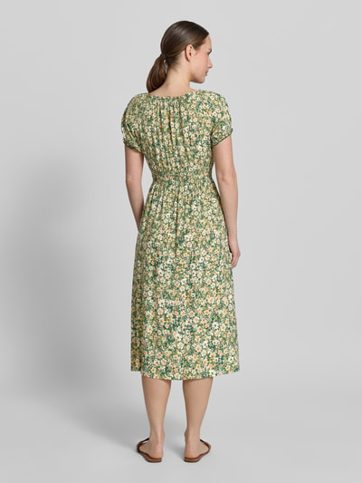 Frauenmodel trägt Midikleid aus Viskose mit Rüschenärmeln von Apricot, florales Muster, Taillierter Schnitt, Ganzkörperansicht Rückansicht. Rückenlänge bei Größe S: 113 cm, Brustweite: 29 cm, Ärmellänge: 16 cm, Reine Viskose, Rundhalsausschnitt mit Rüschen, Schnürung, Rüschenärmel, Smok-Detail.