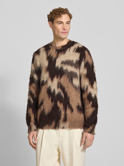Männermodel trägt Regular Fit Strickpullover mit Lanawoll-Anteil Modell 'Forrest' von Les Deux, abstraktes braun-beiges Muster, Ganzkörperansicht von vorne. Elastischer Material-Mix, gerippte Abschlüsse, Rundhalsausschnitt, langärmelig.