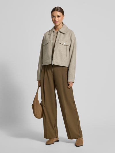 Modelka nosi Regular Fit Hemdjacke mit Reißverschluss Modell 'FORTUNEFREJ' od Vero Moda, jednolity filc, krój regular fit, jasny beż, duże klapy, długie rękawy, kieszenie z patkami, widok całej sylwetki z przodu.