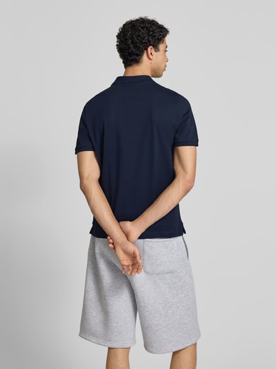 Männermodel trägt Slim Fit Poloshirt mit Label-Stitching von REVIEW in Dunkelblau, Reine Baumwolle, Ganzkörperansicht Rückansicht.