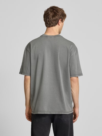 Männermodel trägt Oversized Fit T-Shirt mit Logo-Stitching von Pegador in Grau, Reine Baumwolle, Rundhalsausschnitt, Herren T-Shirt, Ganzkörperansicht Rückansicht. Rückenlänge bei Größe M: 71 cm.