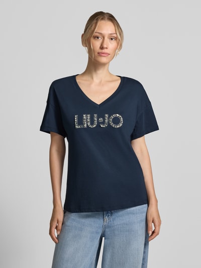 Frauenmodel trägt Regular Fit T-Shirt aus reiner Baumwolle von Liu Jo White in Dunkelblau mit Ziersteinbesatz und Logo-Detail, Ganzkörperansicht von vorne.