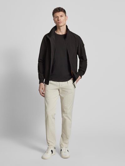 Männermodel trägt Windbreaker mit Stehkragen Modell 'YETUR' von CARS JEANS, Material-Mix mit Stretch-Anteil, Gerader-Schnitt, Reißverschluss, Reißverschlusstasche am Arm, elastische Abschlüsse, schwarze Farbe auf cremefarbener Hose, glatte Textur, Ganzkörperansicht von vorne. Rückenlänge in Größe M: 71 cm, Schulterbreite: 44 cm, Brustweite: 50 cm, Ärmellänge: 68 cm.