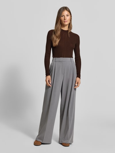 Frauenmodel trägt Strickpullover mit Woll-Anteil von MYON, braun, eng anliegend, Ripp-Optik, Stehkragen, Ganzkörperansicht von vorne.