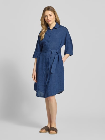 Vrouwenmodel draagt Leinenkleid aus reinen Leinen Modell 'Derby' van 0039 Italy in donkerblauw, semi-transparant, getailleerd, met halflange mouwen, platte kraag, doorlopende knoopsluiting en afneembare stoffen band, context: ruglengte maat S 96 cm, borstwijdte 59 cm, mouwlengte 24 cm, vooraanzicht volledige lichaamsopname.