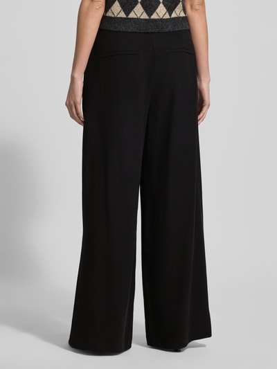 Frauenmodel trägt Hose aus Viskose-Mix mit weitem Bein von MAC in Schwarz mit Gesäßtaschen, Gelegte Falten, Ganzkörperansicht Rückansicht. Bundweite bei Größe 36/32: 40 cm, Innenbeinlänge: 81 cm.