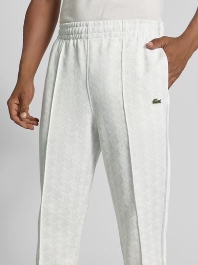 Männermodel trägt Regular Fit Sweathose mit Baumwoll-Anteil von Lacoste in Weiß mit Rautenmuster, Nahaufnahme Oberkörper. Herren Sweathose von Lacoste.