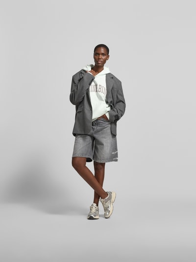 Frauenmodel trägt Oversized Hoodie mit Logo-Stitching von Anine Bing aus reiner Baumwolle, Oversized-Fit, Kapuze, Känguru-Tasche, Rückenlänge 64 cm, Ganzkörperansicht von vorne.