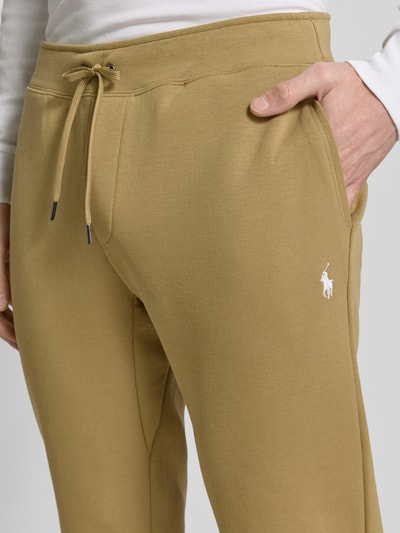 Männermodel trägt Tapered Sweatshorts aus Baumwoll-Mix von Polo Ralph Lauren w kolorze jednolitym, wyhaftowane logo, tunel, elastyczny ściągacz, wpuszczane kieszenie, kieszeń z tyłu, dzianina dresowa, mieszanka bawełny, zbliżenie na górną część spodenek.