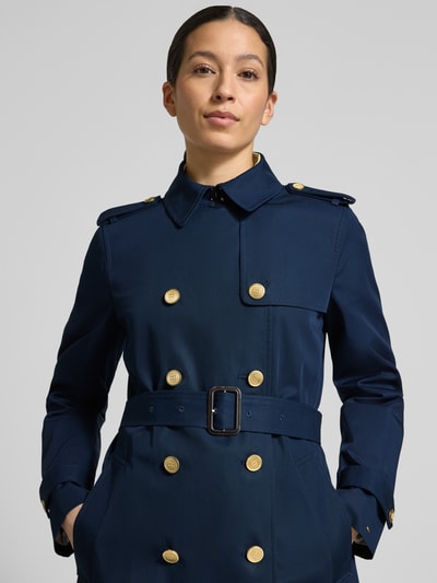 Frauenmodel trägt Slim Fit Trenchcoat aus reiner Baumwolle von Tommy Hilfiger in Dunkelblau mit goldfarbenen Knöpfen, Nahaufnahme Oberkörper.