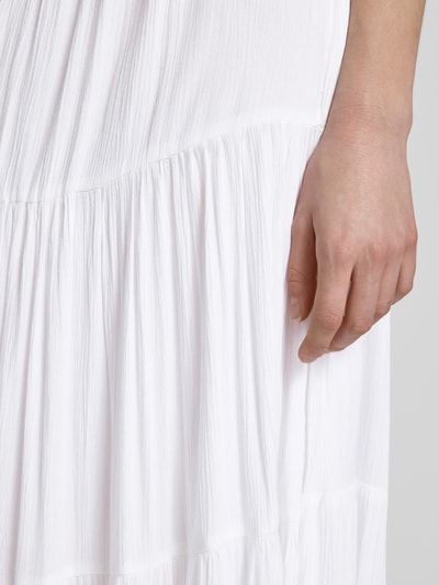 Vrouwenmodel draagt Maxirock im Stufen-Look van REVIEW in wit, A-lijn van zuivere viscose met tunnelkoord, detailopname heup en hand.