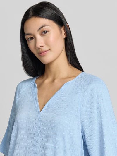 Frauenmodel trägt Relaxed Fit Kurzarmbluse aus Viskose-Mix von s.Oliver RED LABEL in Hellblau mit feiner Struktur, Nahaufnahme Oberkörper.
