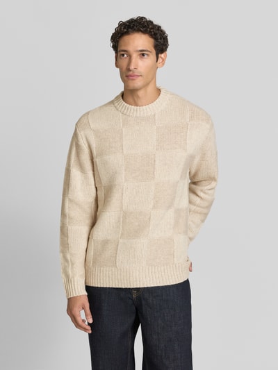 Männermodel trägt Strickpullover mit geripptem Rundhalsausschnitt von Les Deux aus reiner Baumwolle, beige Karomuster, gerader Schnitt, Ganzkörperansicht von vorne.