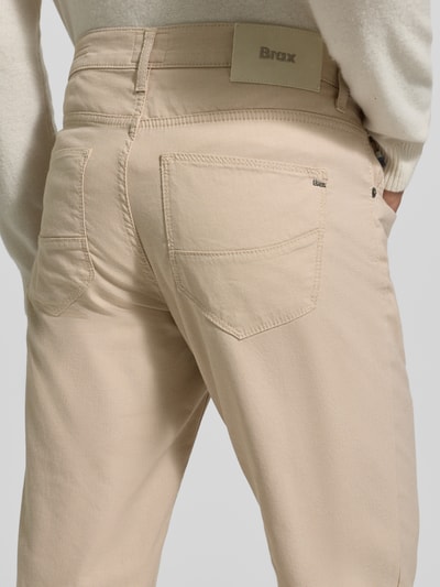 Männermodel trägt Slim Fit Stoffhose mit 5-Pocket-Design Modell 'Cadiz' van Brax, beige katoenmix met stretch, detailopname rug.
