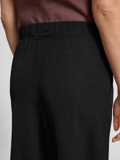 Frauenmodel trägt Culotte mit Kordelzug und Eingrifftaschen von Französische, schwarze Textur, elastischer Bund, Nahaufnahme Rückansicht.
