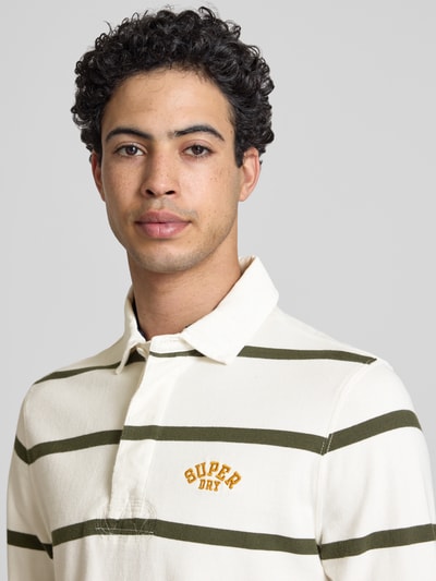 Männermodel trägt Regular Fit Poloshirt mit Logo-Stitching von Superdry aus Reiner Baumwolle, Streifenmuster, Nahaufnahme Oberkörper.