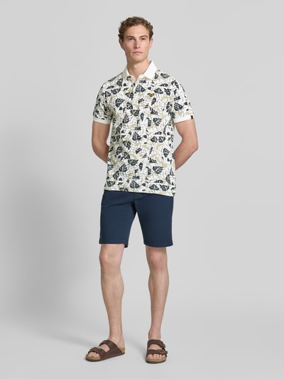 Männermodel trägt Slim Fit Poloshirt im Allover-Look von PME Legend aus Baumwoll-Elasthan-Mix, Knopfleiste, Label-Stitching, marineblaue Shorts, Ganzkörperansicht von vorne. Rückenlänge bei Größe M: 72 cm.