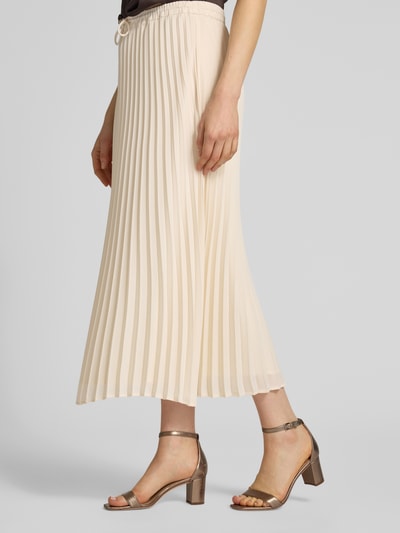 Vrouwenmodel draagt Midirock mit Plisseefalten van comma in A-lijn, elastische tailleband met strik, crèmekleur, midi lengte, detailopname linkerzij.