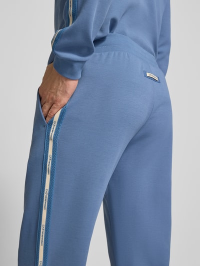 Männermodel trägt Sweatpants mit elastischem Bund von EA7 Emporio Armani in Blau mit weißen Seitendetails, Nahaufnahme Rückansicht. Herren Sweatpants, Regular Fit, Baumwoll-Mix, Innenbeinlänge 80 cm bei Größe M.